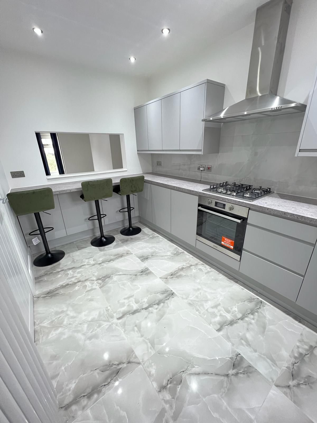 Fitted kitchen with grey cabinetry and bar seating in a four-bedroom Harrow property managed by FNJ Group